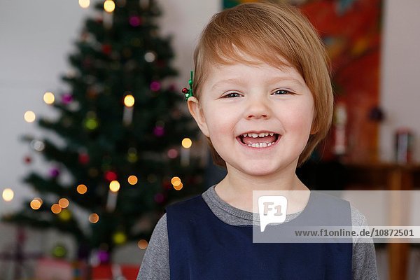 Portrait of girl in front of christmas tree smiling