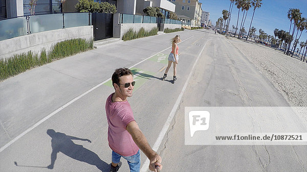 Rear view of rollerblading couple taking selfie  Venice Beach  California  USA