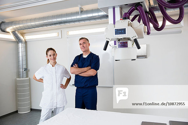 Portrait of doctor and nurse next to medical x-ray equipment in hospital