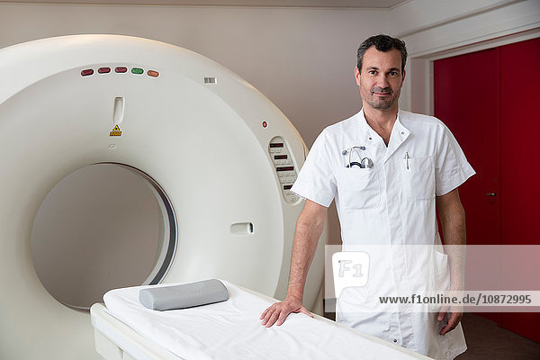 Portrait of doctor standing next to CT-scanner