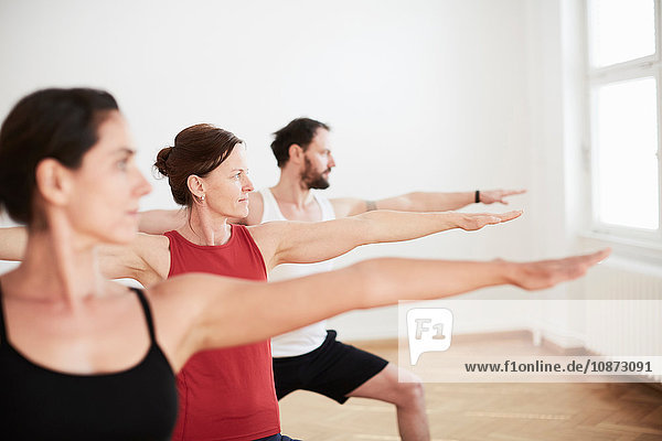People in exercise studio arms open in yoga position