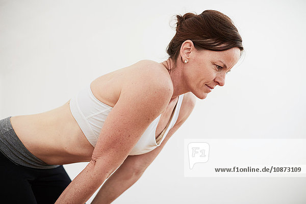 Woman in exercise studio wearing crop top bending forward