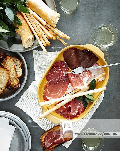 Overhead view of meal with dish of salumi and pane carasau (bread)