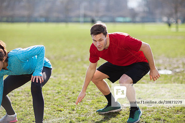 Junger Mann und Frau beim körperlichen Training auf dem Spielfeld