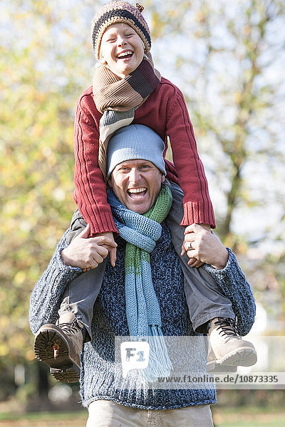 Father and son in park  father carrying son on shoulders  laughing