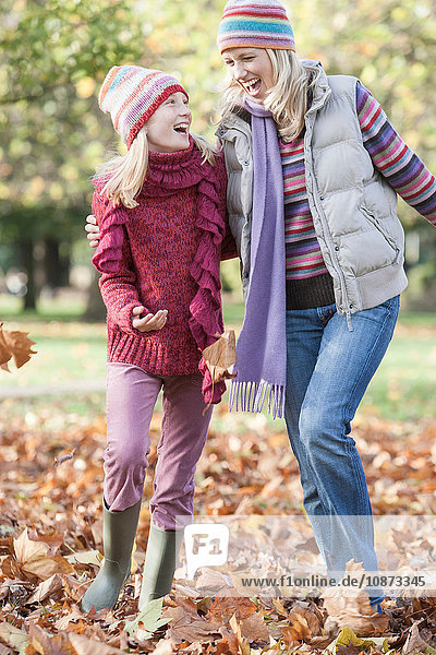 Mutter und Tochter beim Herumtollen im Park  beim Spaziergang durch das Herbstlaub
