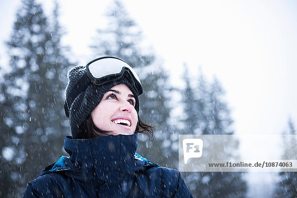 Portrait of young woman wearing ski goggles looking up at snow  Brighton Ski Resort outside of Salt Lake City  Utah  USA