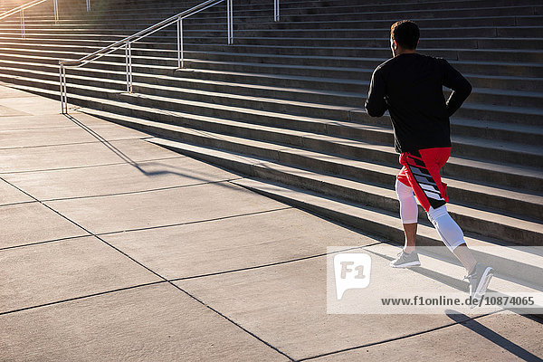 Young male runner running past city stairway