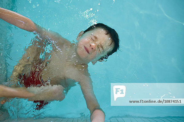 Junge mit geschlossenen Augen  mit Kopf über Wasser im Schwimmbecken