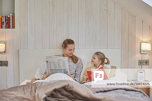Mutter und Tochter beim Lesen im Bett