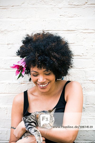 Portrait of woman with flower in hair  cat in arms