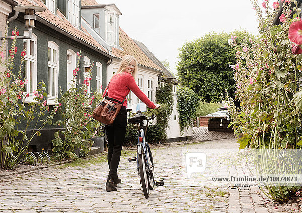 Frau schiebt Fahrrad auf Kopfsteinpflasterstraße  Aarhus  Dänemark