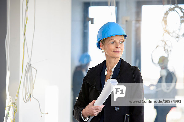 Porträt einer Geschäftsfrau  die die Blaupause im neuen Amt hält