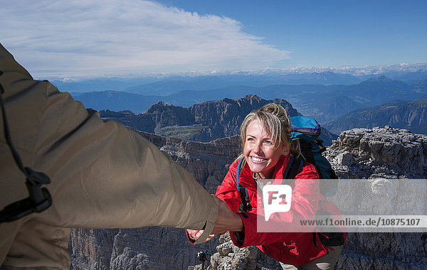 Ein Bergsteiger hilft seiner Partnerin auf den Gipfel eines Berges  Dolomiten  Italien
