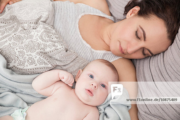 Mother lying on bed with baby boy  overhead view