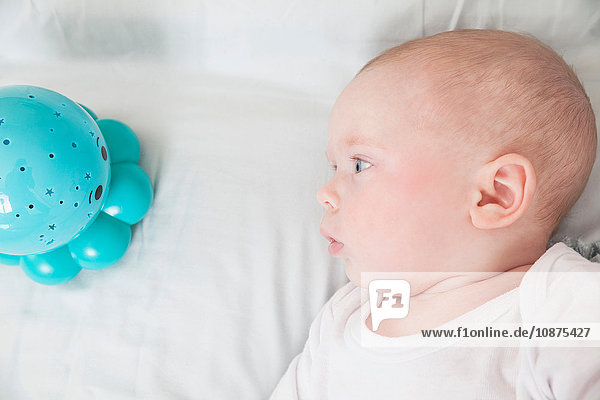 Baby boy staring at blue baby toy  overhead view