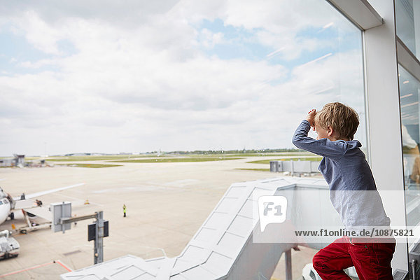 Boy looking out of airport window at runway