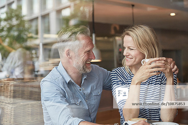 Blick durch das Fenster eines reifen Paares im Café von Angesicht zu Angesicht lächelnd