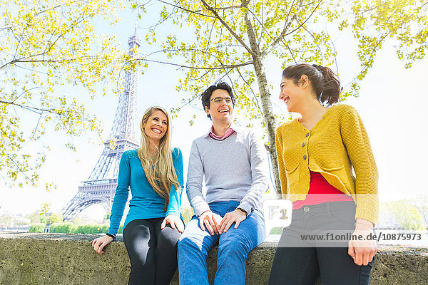 Freunde sitzen lächelnd an der Wand Paris Frankreich