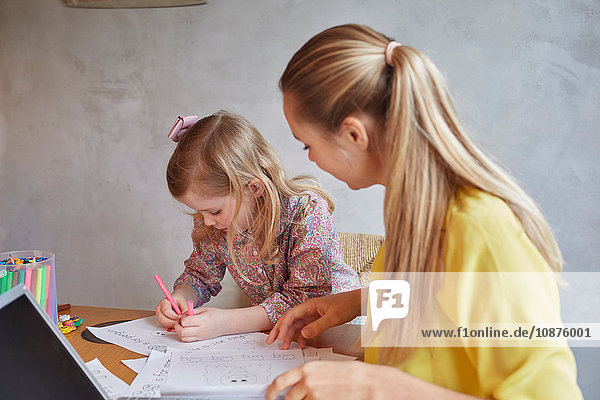 Mother teaching daughter to write at desk