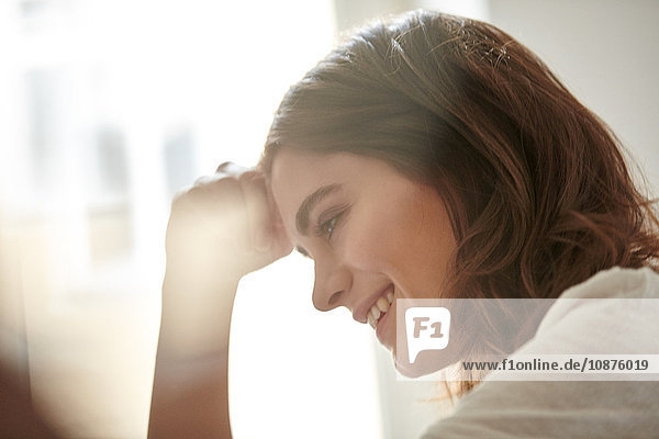 Happy young woman at home in front of window