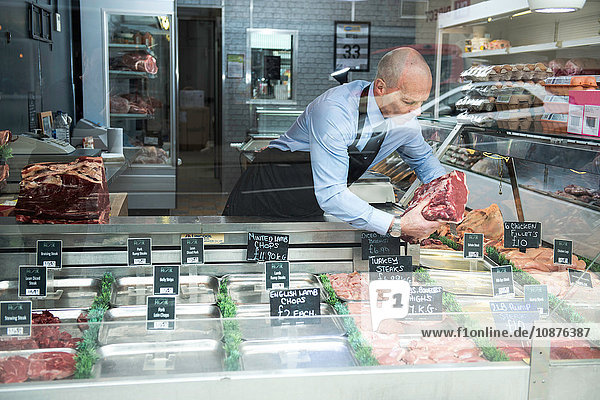 Butcher preparing window display in butcher's shop