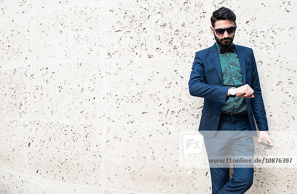 Mid adult businessman outdoors holding smartphone looking at watch