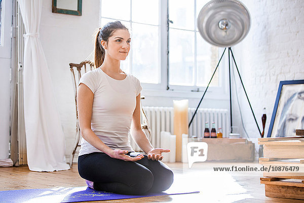 Junge Frau praktiziert Yoga-Meditation in Wohnung