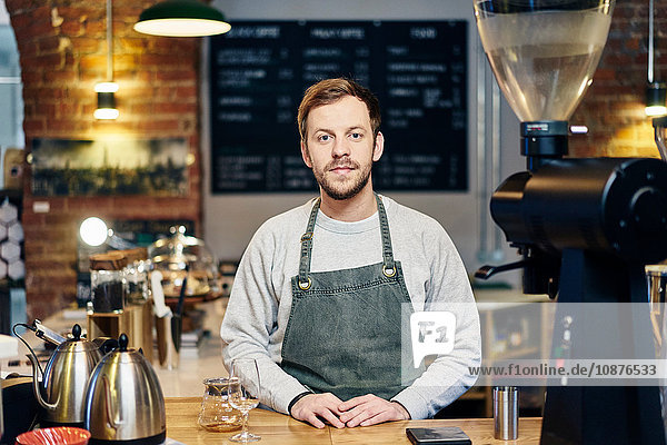 Porträt eines jungen männlichen Barista an der Kaffeehaus-Küchentheke