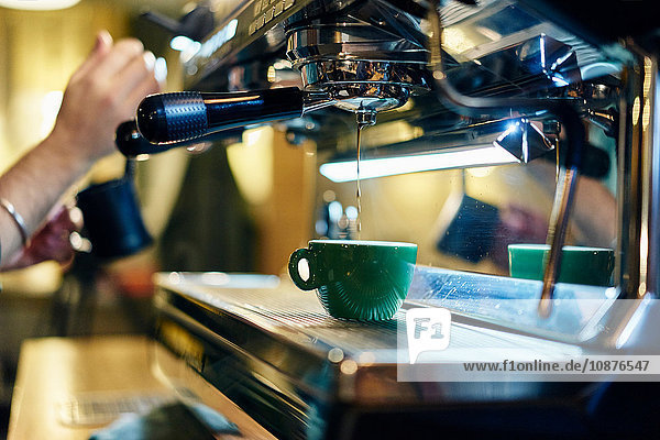 Hände eines männlichen Barista beim Erhitzen des Milchkännchens auf der Kaffeemaschine im Café