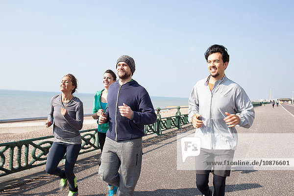 Männliche und weibliche Läufer laufen gemeinsam am Strand von Brighton