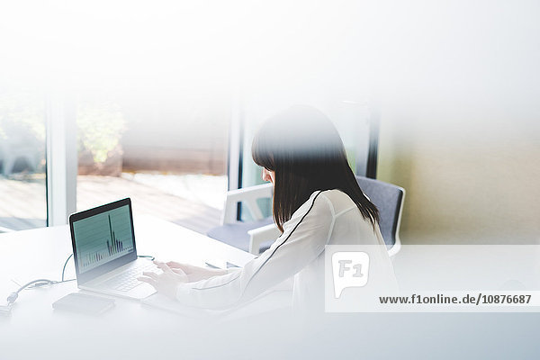 Fensteransicht einer Geschäftsfrau mit Laptop am Büroschreibtisch