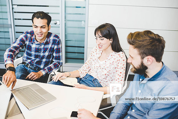 Three young designers using laptop at office meeting