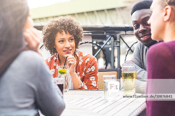Friends in beer garden at table enjoying a drink, smiling