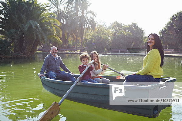 Familie im Ruderboot auf dem See schaut lächelnd in die Kamera