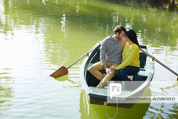 Paar im Ruderboot auf dem See Kopf an Kopf umarmend