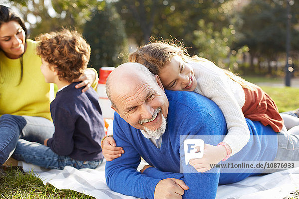 Mädchen im Park liegt lächelnd auf Großvater