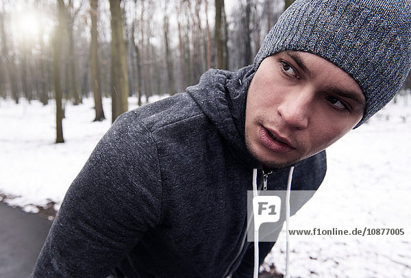 Young man exercising in snowy forest  looking away