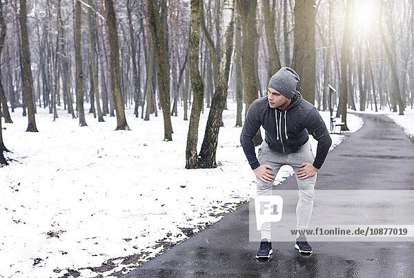 Junger Mann macht eine Pause vom Sport im verschneiten Wald