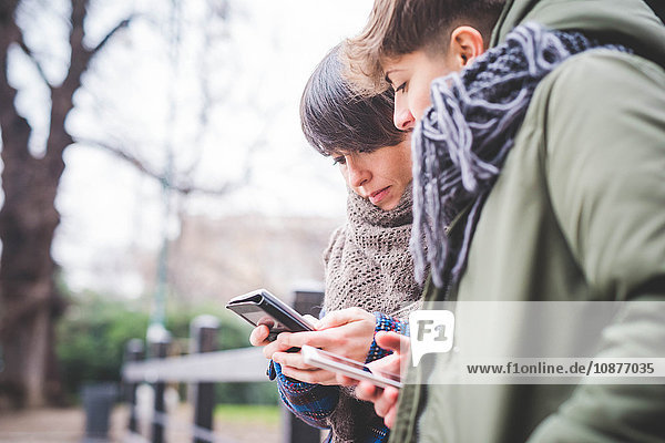 Two sisters looking at smartphone  outdoors