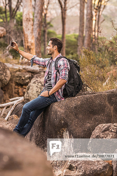 Male hiker taking smartphone selfie on forest rock formation  Deer Park  Cape Town  South Africa