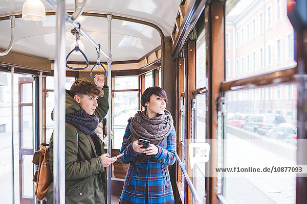 Two sisters riding cable car  holding smartphones