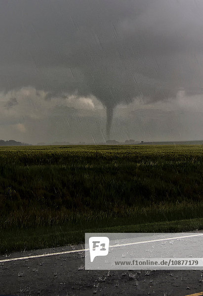 Ein fast regennassender Tornado landet in der Nähe einer Farm in Kansas  im Vordergrund Hagel auf der Straße