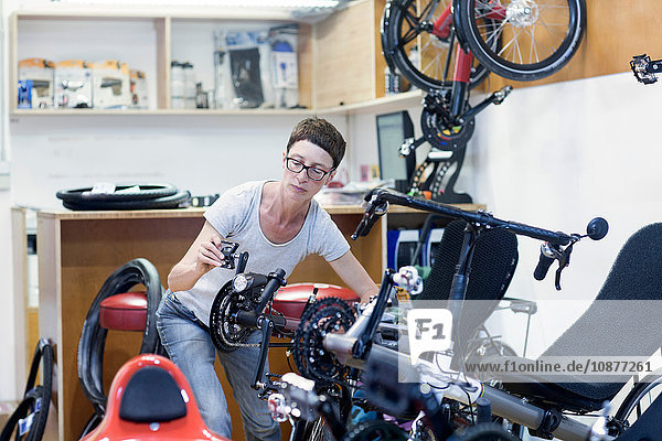 Woman in bicycle workshop checking pedal on recumbent bicycle