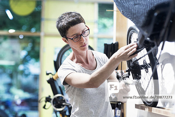 Frau in Fahrradwerkstatt repariert Rad auf Liegefahrrad
