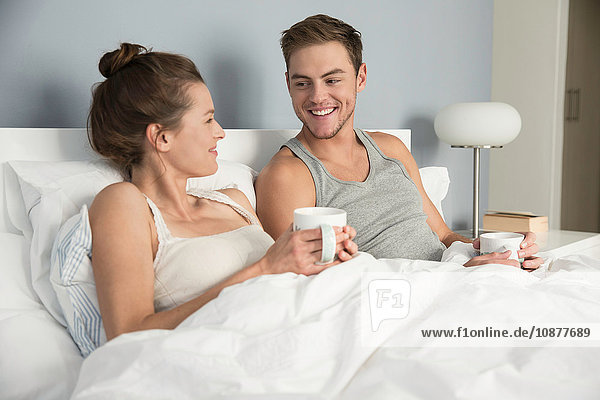 Junges Paar trinkt Kaffee im Bett