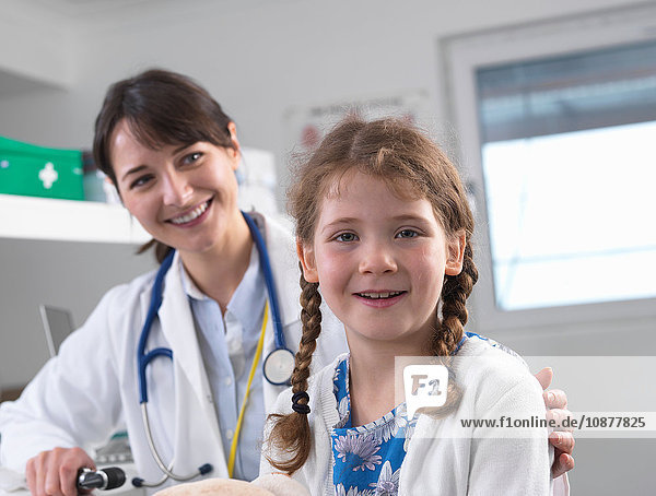 Pediatrician and girl looking at camera smiling