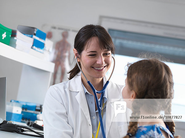 Pädiatrische Ärztin  die in einer Klinik die Brust eines jungen Mädchens mit einem Stethoskop abhört