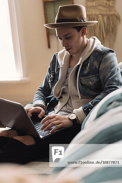 Junger Mann entspannt sich zu Hause  mit Laptop