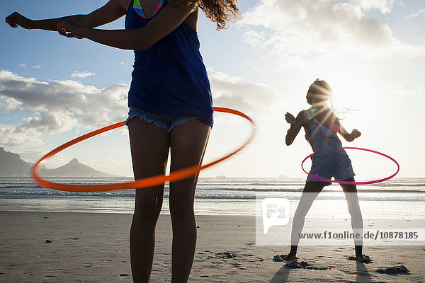 Young women on beach using hula hoops
